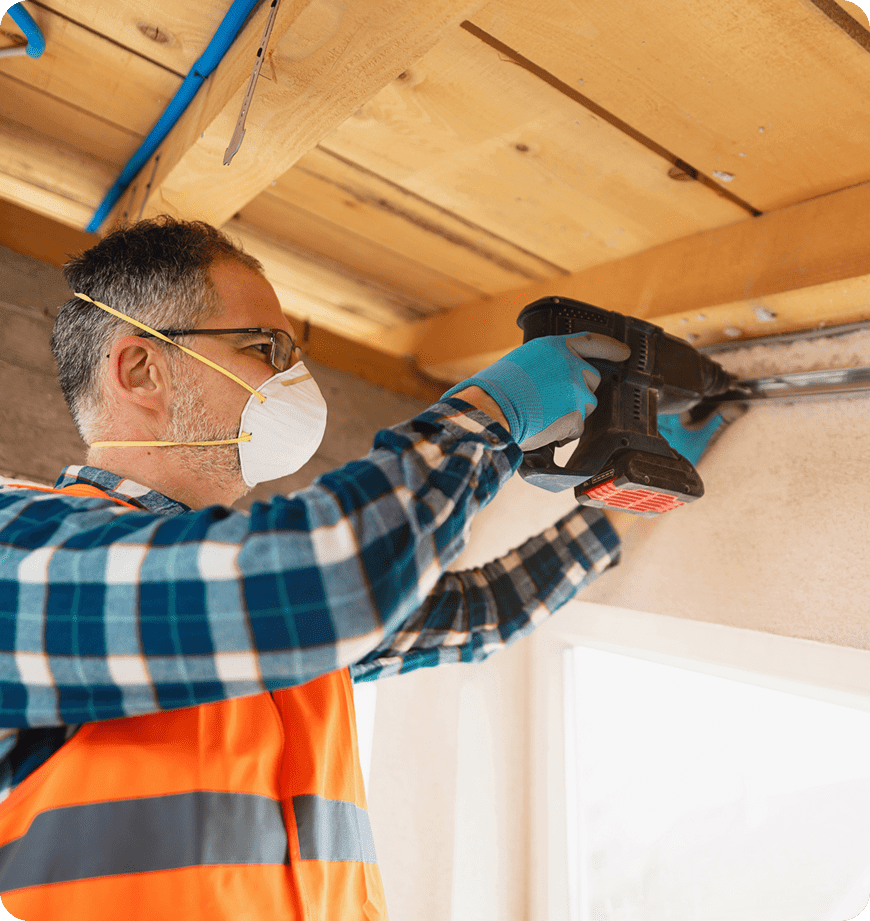 A contractor drilling the ceiling to prepare for insulation installation.