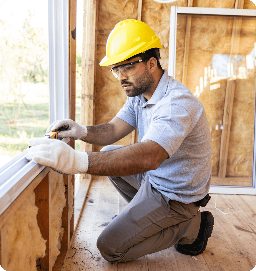 Construction worker measuring a window frame in a house.