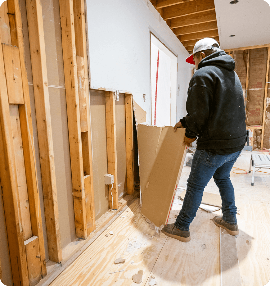Man removing wood panels during a home renovation.