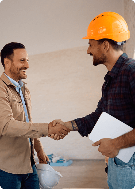 Two men shaking hands, construction setting.