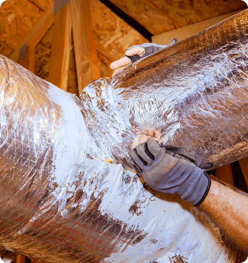 An HVAC technician applies white sealant to silver ductwork insulation and sealing.