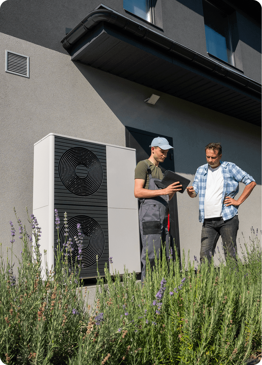 Two men examining air conditioning unit outside.