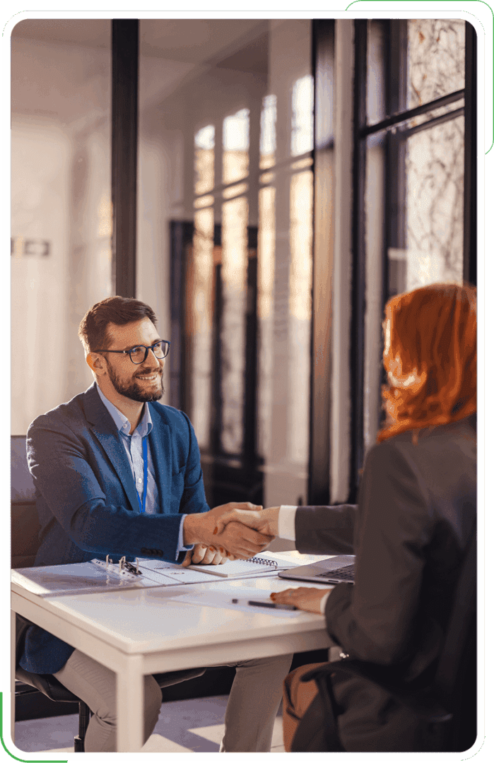 Two people shaking hands in office.