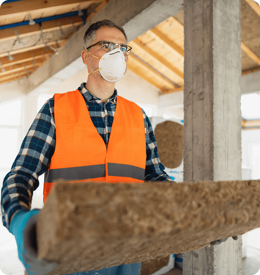 A worker wearing a mask carrying material for an insulation installation.