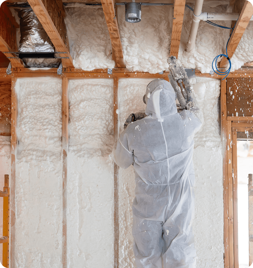 Worker applying spray foam insulation indoors.