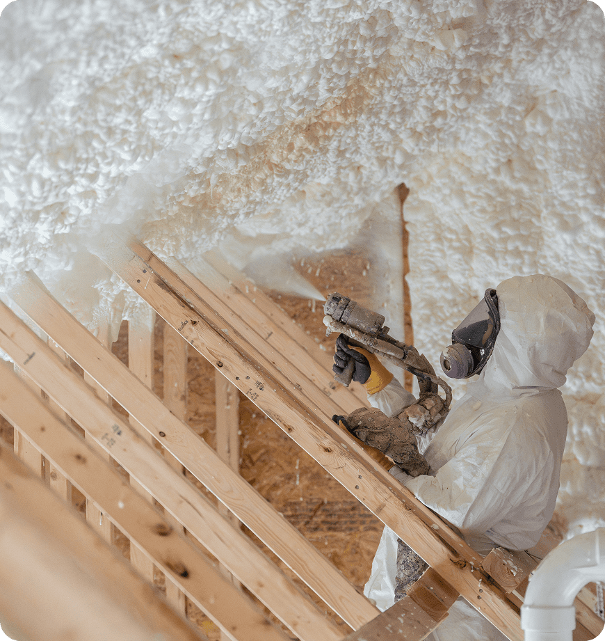 Worker applying spray foam insulation in attic.