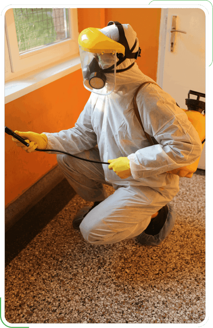 A man in a white suit delivers pest control to residential walls.