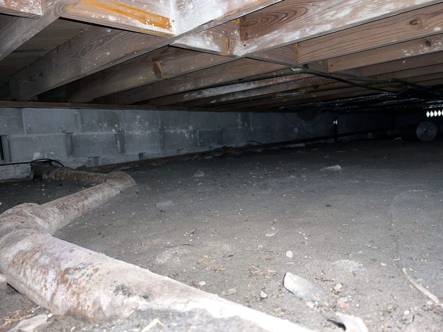 Crawlspace with exposed pipes and wooden joists