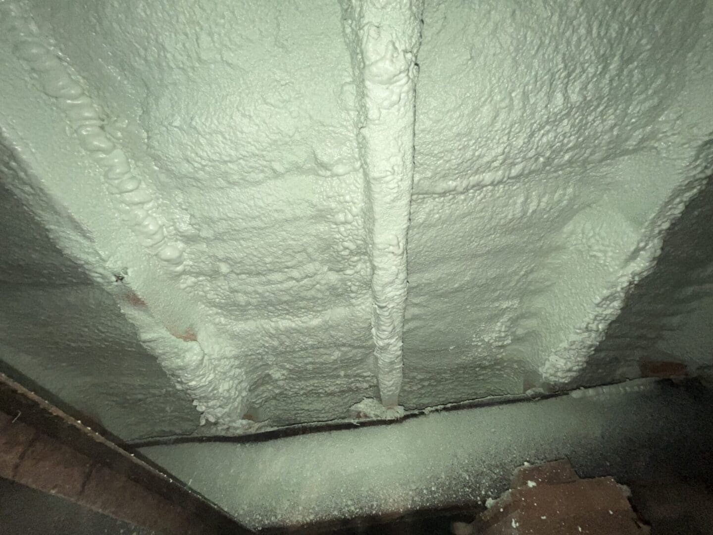 Spray foam insulation on wooden ceiling beams.