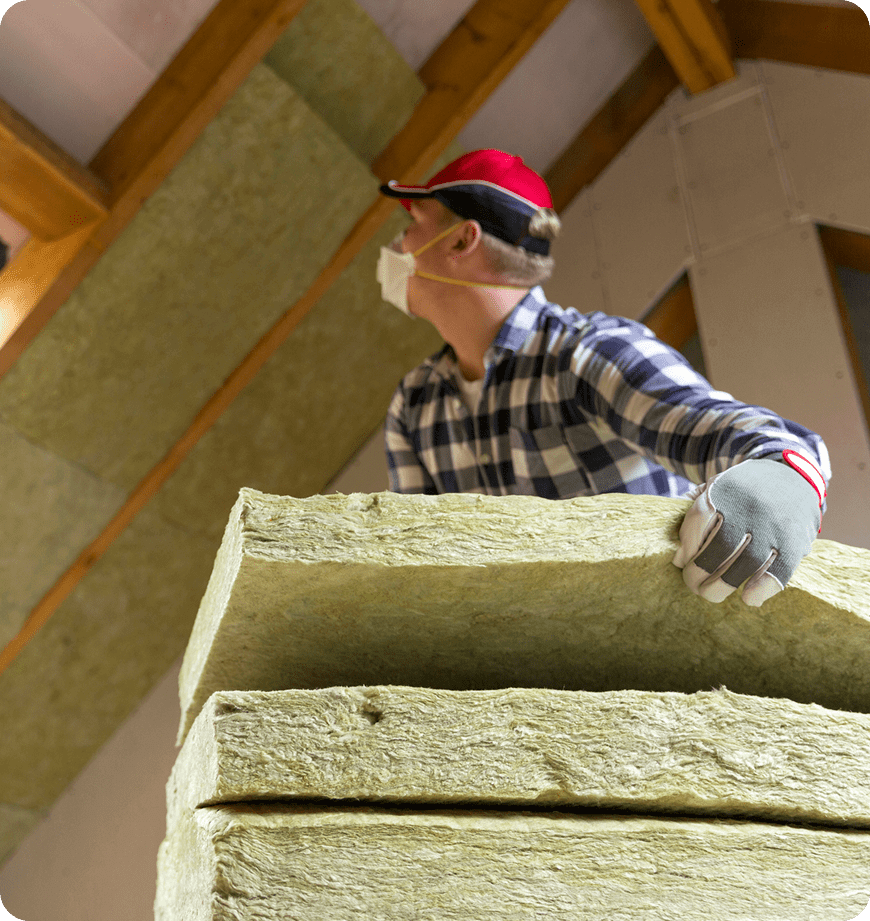 Worker wearing mask and gloves holding mineral wool insulation batts.