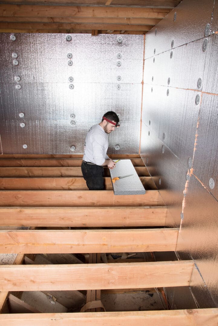 Man installing insulation in unfinished room.