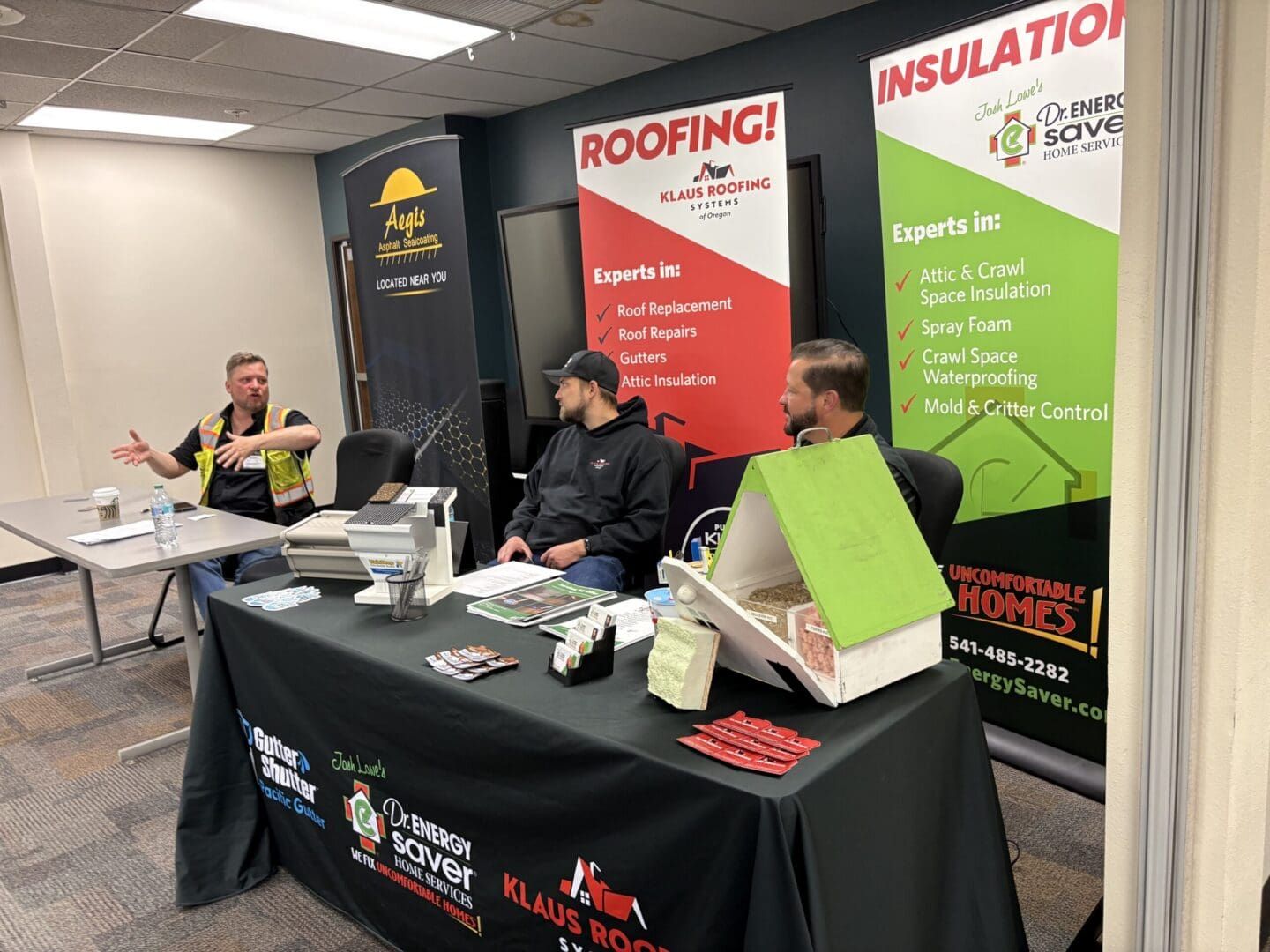 Three men at roofing and insulation exhibition booth